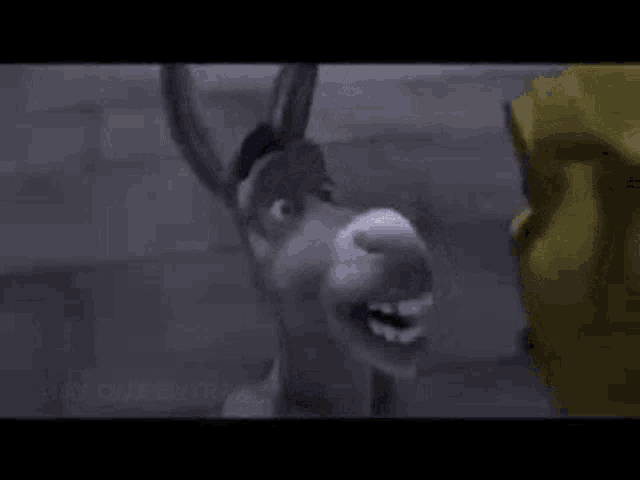 a donkey is standing next to shrek in a dark room and talking to him .