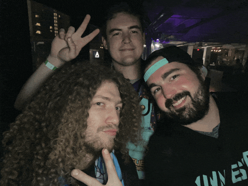 three men are posing for a picture with one wearing a shirt that says ' i love ' on it