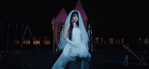 a woman in a wedding dress stands in front of a fire