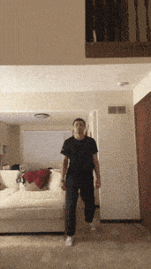 a man in a black shirt is standing in a living room with a white couch