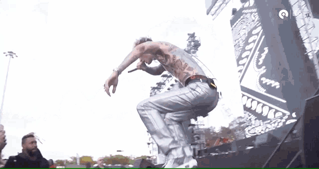 a man with a tattoo on his back is jumping in the air