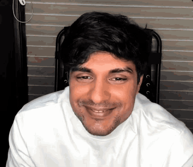 a man with a beard wearing a white shirt smiles for the camera
