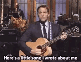 a man in a suit and tie is playing a guitar and saying here 's a little song i wrote about me .
