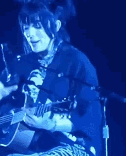 a man is singing into a microphone while playing a guitar on stage .