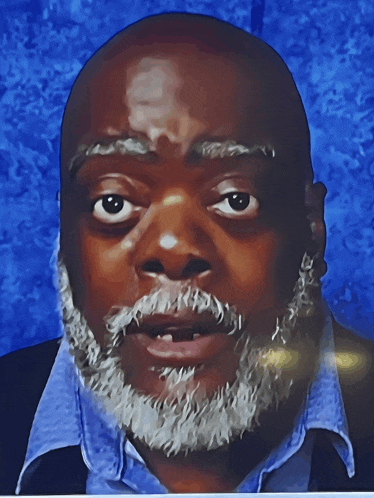 a man with a beard is wearing a blue shirt and a black jacket