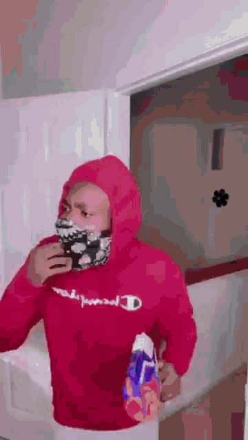 a man wearing a red hoodie and a mask is standing in a doorway .