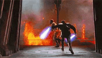 a couple of men are fighting with lightsabers in front of a large fire .