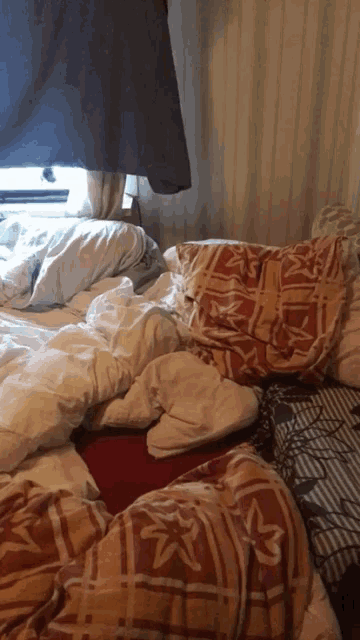 a messy bed with a blanket that has the letter a on it