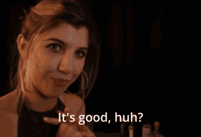 a woman says " it 's good huh " in front of a dark background