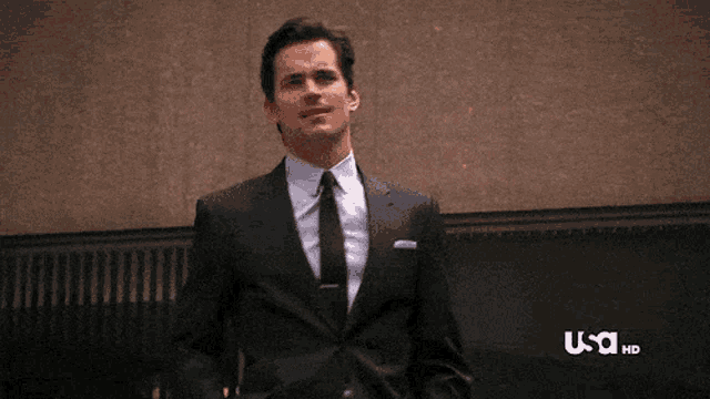a man in a suit and tie is standing in front of a usa hd logo