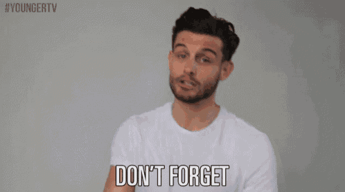 a man with a beard is wearing a white shirt and pointing at the camera .