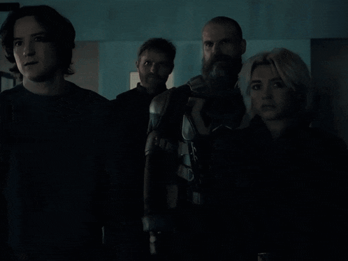 a group of people standing in a dark room looking at the camera