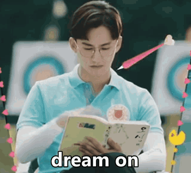 a man in a blue shirt is reading a book with the words dream on above him .