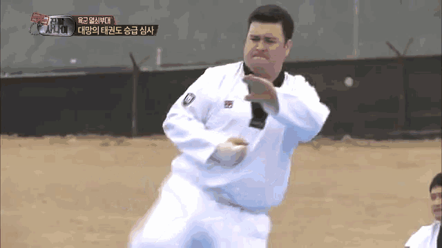 a man in a white uniform is doing a karate move in front of a fence