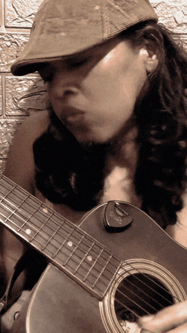 a woman wearing a hat is playing an acoustic guitar with a pick on it