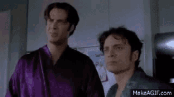 two men are standing next to each other in a kitchen .