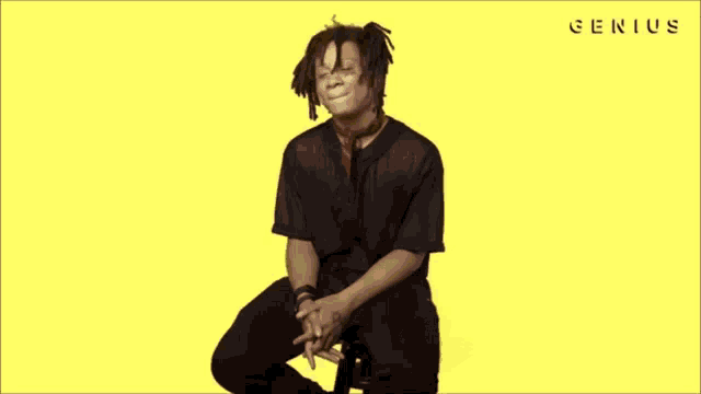 a man with dreadlocks is laughing in front of a yellow background with the word genius written on it