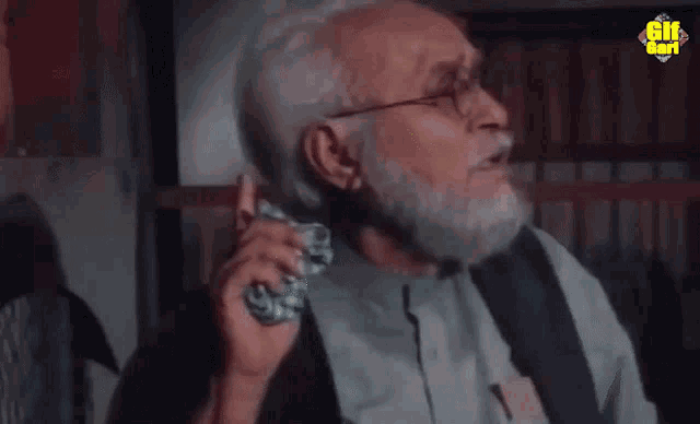 an older man with a beard and glasses is talking on a cell phone with a gif icon above his head