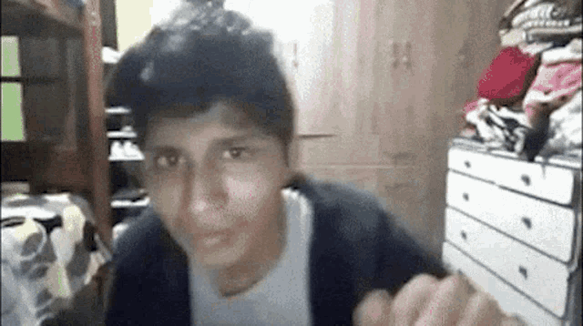 a young man is making a funny face in front of a pile of clothes in a room .