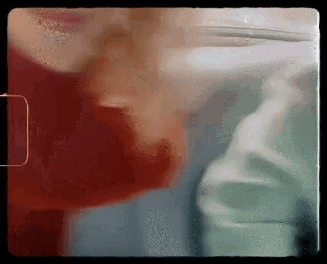 a blurry picture of a person 's face with a red shirt on
