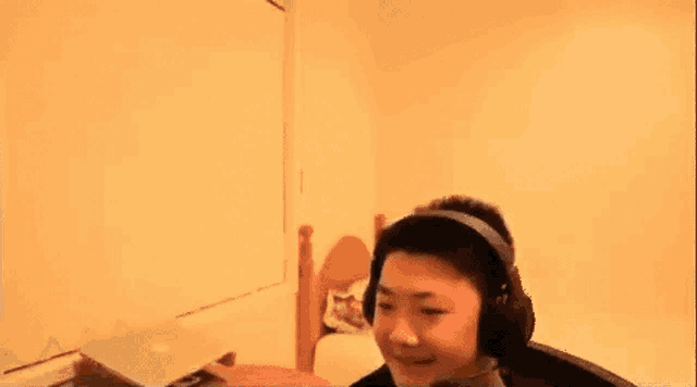 a man wearing headphones is sitting in a room with a laptop .