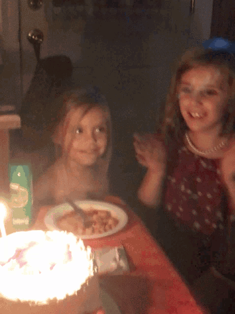 two little girls are sitting at a table with a plate of food and a box that says living on it