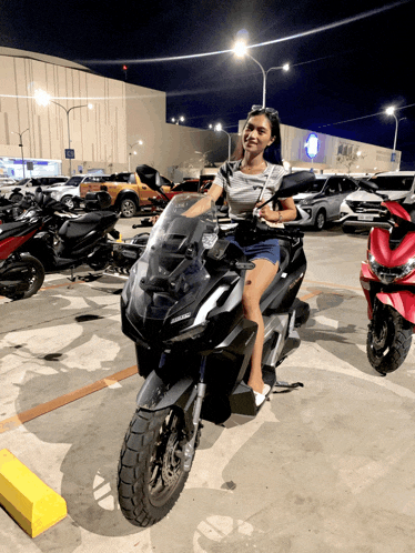 a woman sitting on a motorcycle in a parking lot