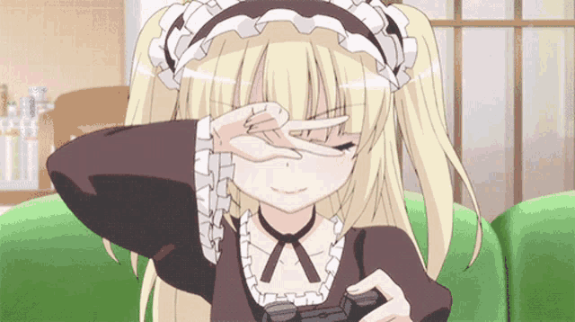 a blonde anime girl is covering her eyes with her hand while holding a video game controller