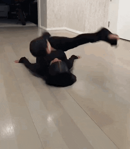 a woman is laying on her stomach on the floor doing a handstand .