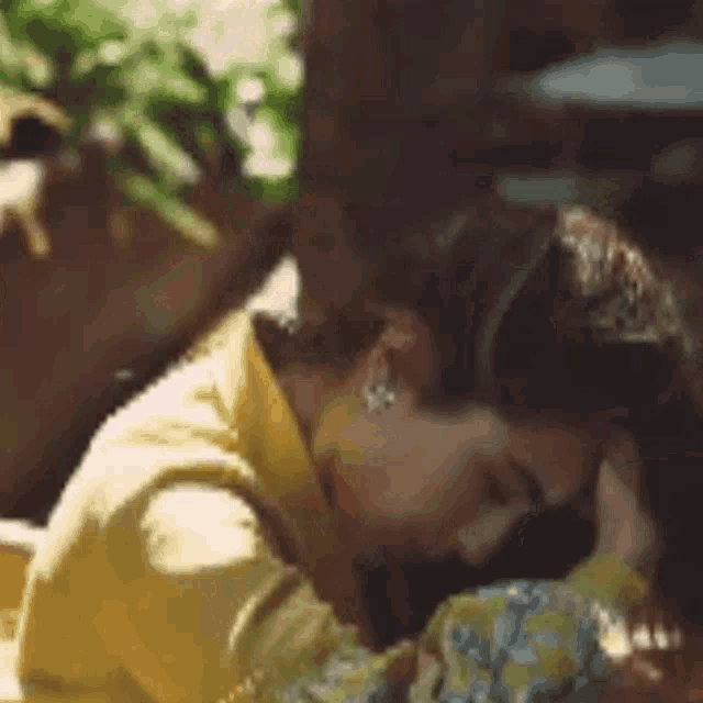 a woman in a yellow shirt is laying down with her head on another woman 's shoulder .