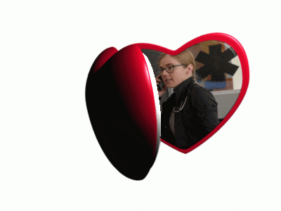 a heart shaped mirror shows a woman talking on a phone