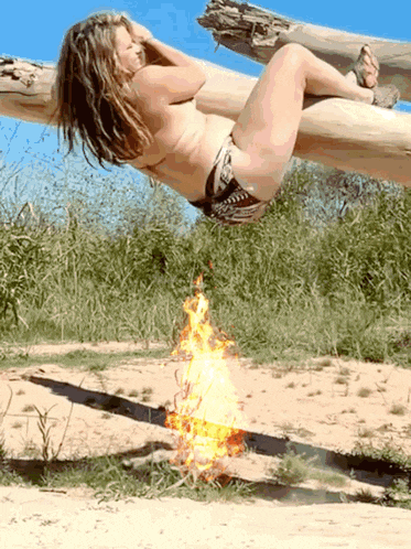 a woman in a bikini is laying on a tree branch