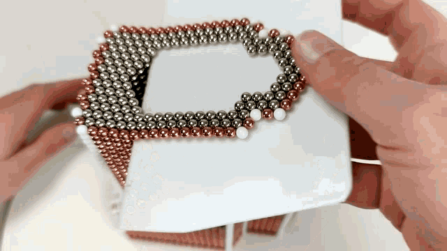 a person is holding a piece of paper that is covered in magnets