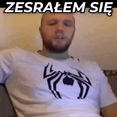 a man wearing a white shirt with a black spider on it