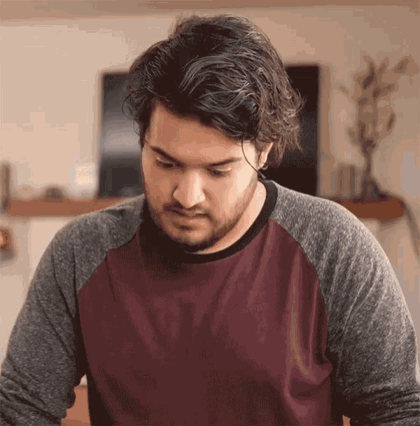 a man with a beard is wearing a maroon and gray shirt