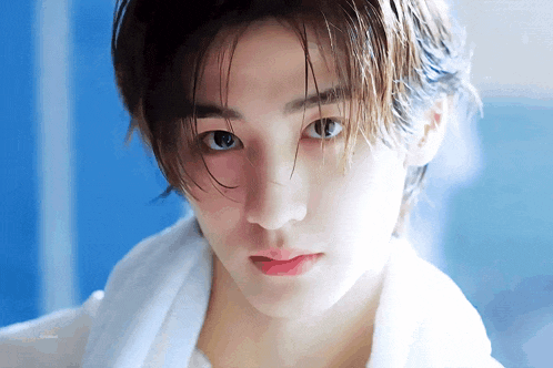 a young man with a towel around his neck looks at the camera