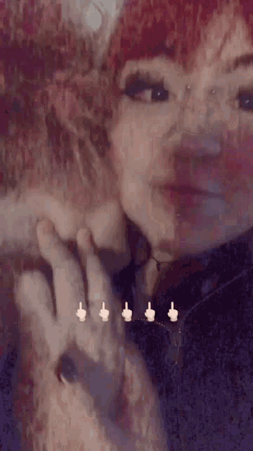 a woman with red hair is holding another woman 's hand and giving her a middle finger .