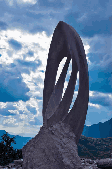 a large stone sculpture with mountains in the background and a cloudy sky