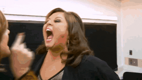 a woman is screaming with her mouth wide open while another woman looks on