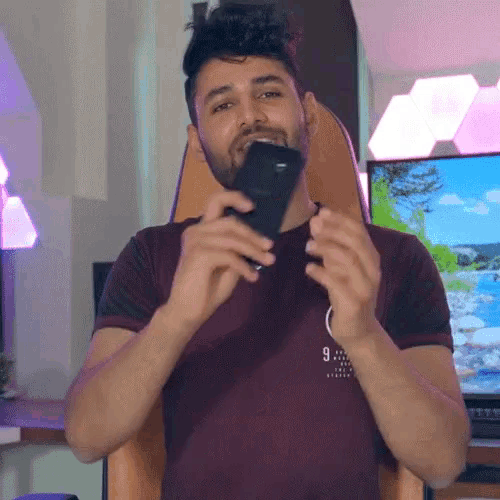 a man in a maroon shirt with the number 9 on it holds a cell phone