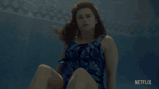 a woman in a blue bathing suit is underwater in a pool with netflix written on the bottom