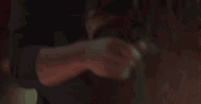 a woman in a black dress is holding a man 's hand in a dark room .