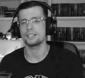 a man wearing headphones and glasses is sitting in front of a bookshelf in a black and white photo .