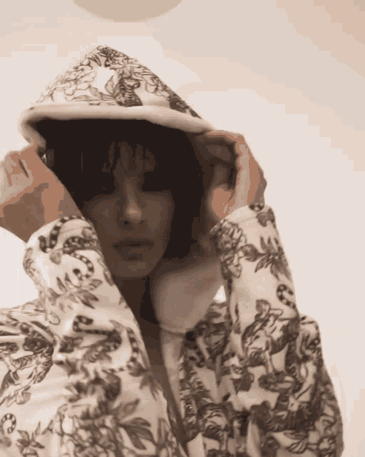 a woman wearing a hooded jacket with a floral print