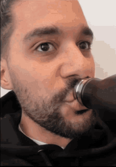 a close up of a man 's face with a bottle in his mouth