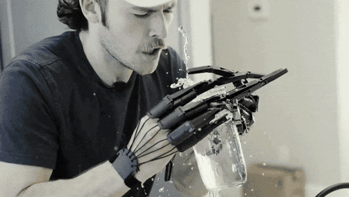 a man wearing a robotic hand is holding a bottle of water