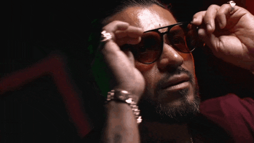 a man with a beard wearing sunglasses and a watch on his wrist