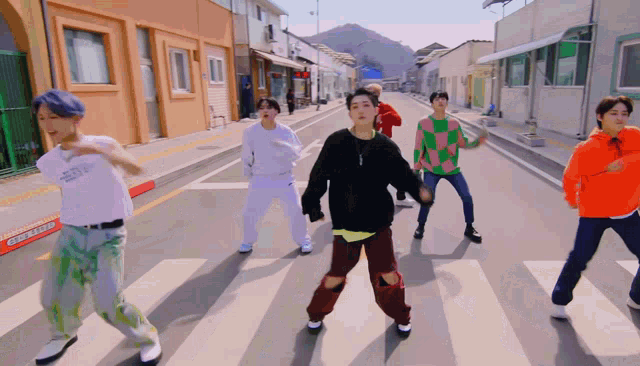 a group of young men are dancing on a street with a sign that says " one way " on it