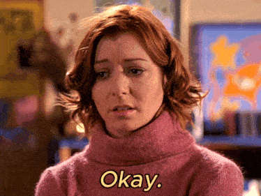 a woman in a pink sweater says okay in yellow letters