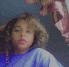a young girl with curly hair is wearing a blue shirt and taking a picture of herself .